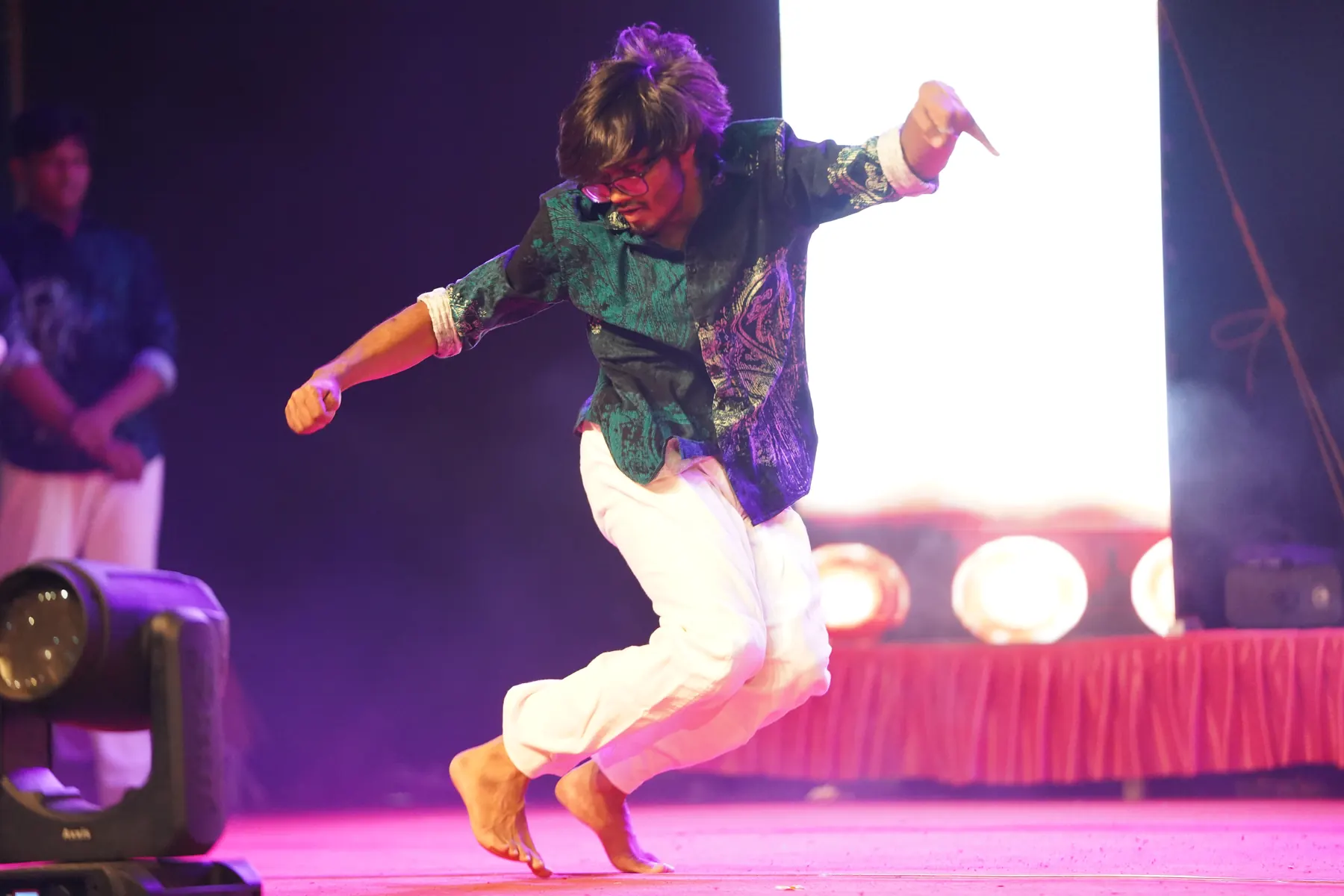 Suhas mid-move on stage under pink lights