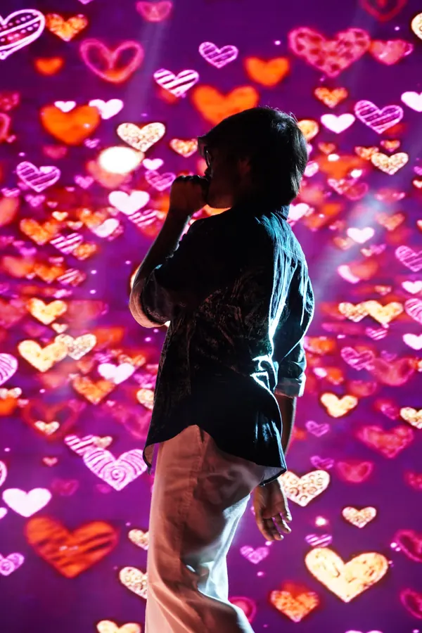 Suhas silhouetted against glowing hearts on the Anokha 2026 stage